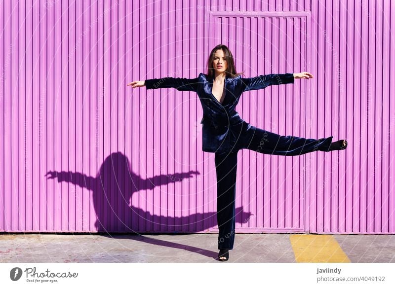 Woman wearing blue suit dancing near pink shutter. woman girl arms leg person fashion model lifestyle female urban background lady one elegant building blind
