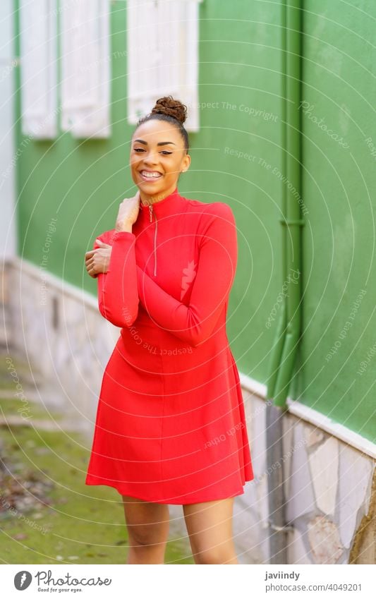 Happy black woman in red dress in front of a green wall smile smiling bow hairstyle model beauty fashion pretty portrait girl happiness young female person lady