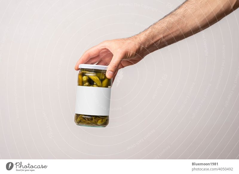 Male hands holding a pickled cucumber glass jar mock-up editable change food blank label brand green container design full golden transparent conserve