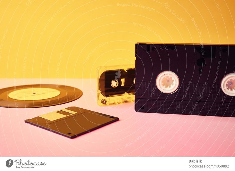Vinyl disc, floppy diskette, vhs and tape cassete on yellow background. Retro and nostalgia concept retro cassette vinyl record vintage music audio