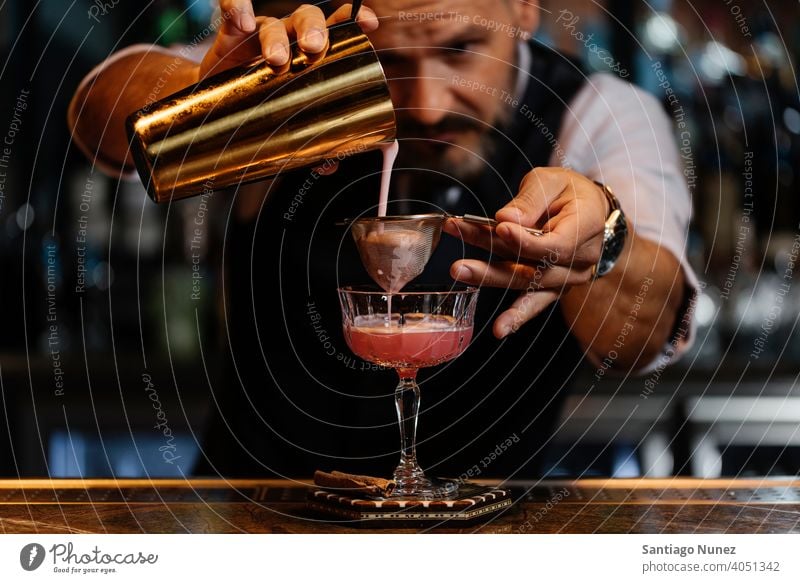 Detail of bartender's hand working in the bar with his shaker and pouring a  cocktail in the glass - a Royalty Free Stock Photo from Photocase