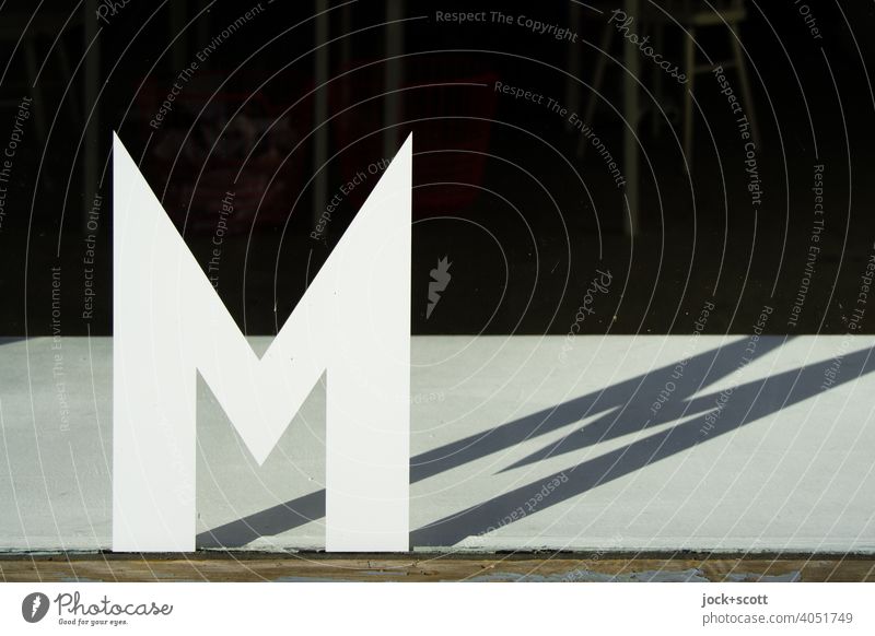 compliant|letter M Capital letter Shop window Sunlight Shadow play Typography Silhouette Neutral Background Individual Pane double Structures and shapes