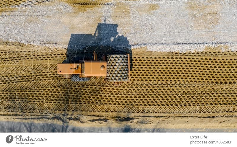 Aerial view on road roller with spikes is working at construction site, compacting base for asphalt road Above Asphalt Base Building Site Civil Engineering