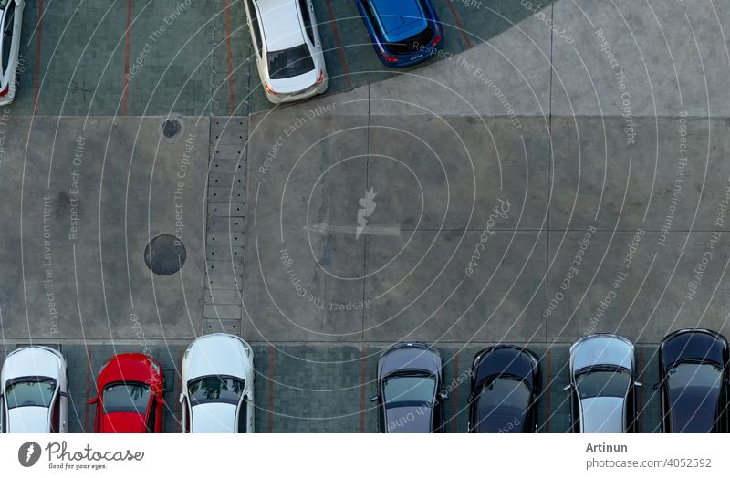 Top view concrete car parking lot. Aerial view of car parked at car parking area of apartment. Outdoor parking space with empty slot. One way traffic sign on road. Above view outside car parking lot.