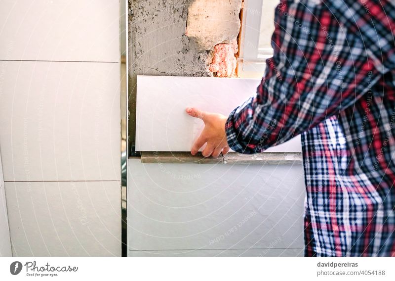 Unrecognizable female bricklayer laying tile on the wall unrecognizable placing bathroom reform copy space position adjusting mason detail hand woman piece