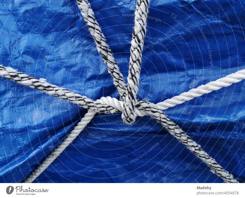 White and black and white ship's rope as a still life on a blue tarpaulin over a boat on a trailer in Oerlinghausen near Bielefeld in the Teutoburg Forest in East Westphalia-Lippe