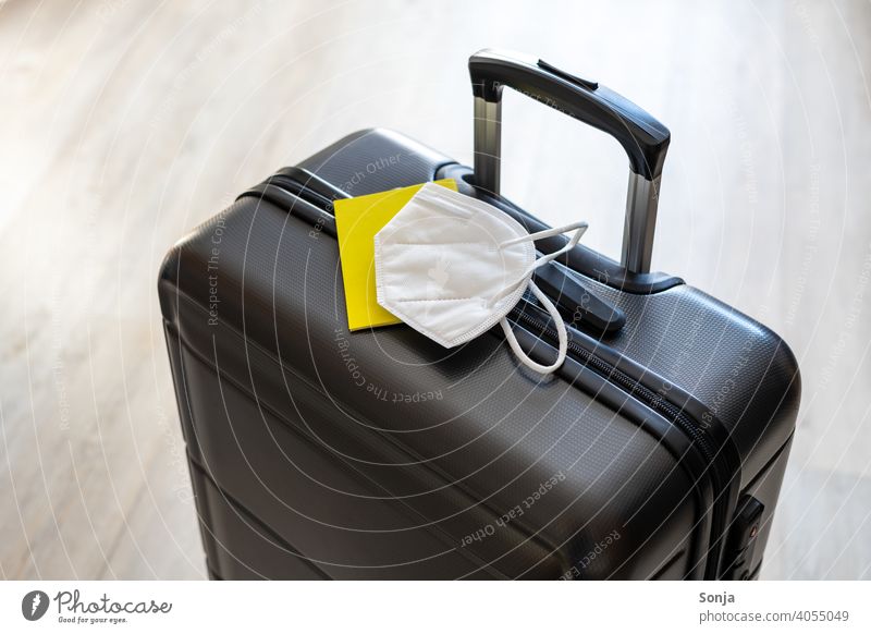 A case with a yellow vaccination certificate and a white FFP2 mask Suitcase voyage Vaccination certificate Yellow ffp2 mask covid-19 coronavirus Mask Protection