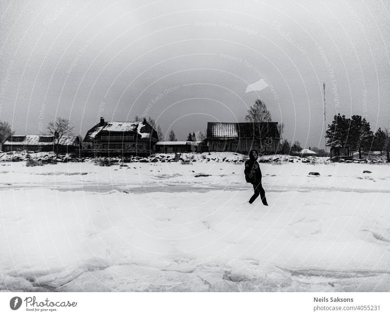 boy throwing up piece of ice on Baltic sea ice winter person house seashore water vacation joy joyful fun black dress having fun walk Walk on the beach