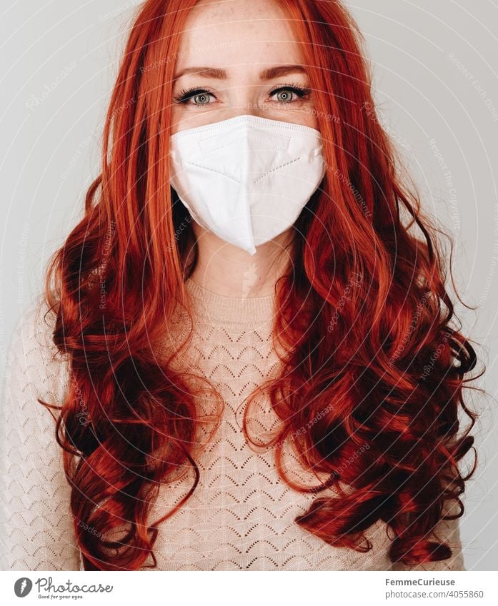 Woman with long red curly hair and FFP2 mask looking into camera with smiling eyes - portrait smilingly Smiling ffp2 Mask Face mask red hair long hairs