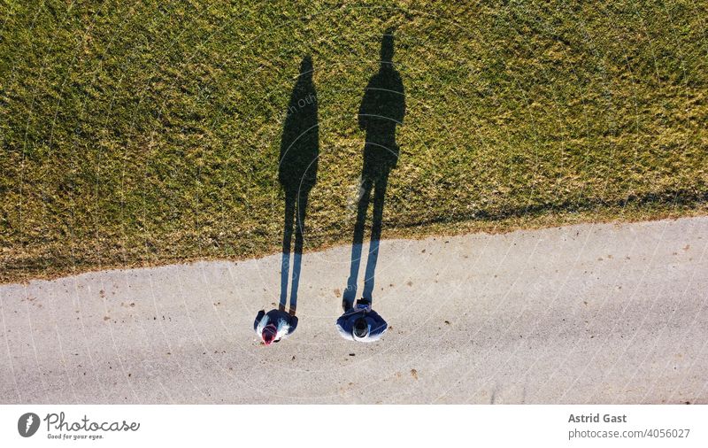 Aerial shot with a drone of two people with a long shadow Aerial photograph drone photo persons Man Woman Couple Street Meadow Field Shadow Sports off