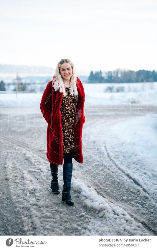 young woman 30 years in snow with red coat and leopard dress blond hair curls joy hopeful street, black boots fashion Woman Dress leopard Model outdoor Snow