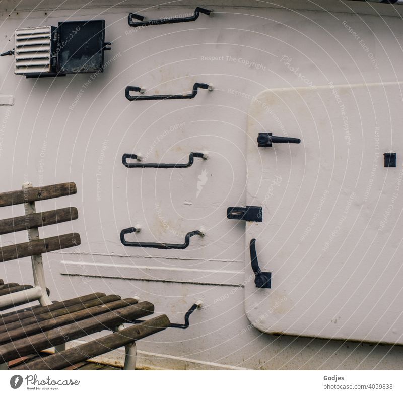 Seating in front of a metal ship's wall with steps and hatchway Navigation Watercraft bench door Hatch Stairs Ladder Exterior shot Day Colour photo Harbour Old