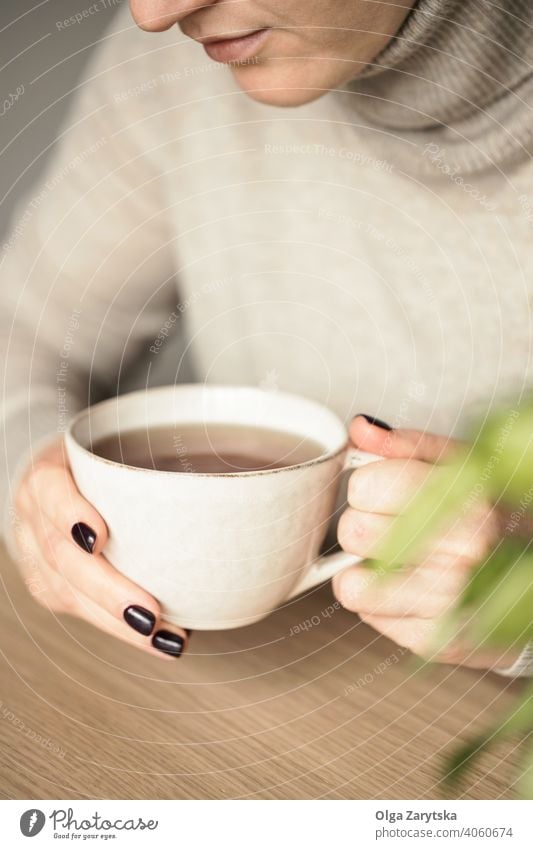 Woman holding a cup of tea. woman relax hand cosy drink close up caucasian break lifestyle girl morning comfort day adult sweater indoor soft focus table