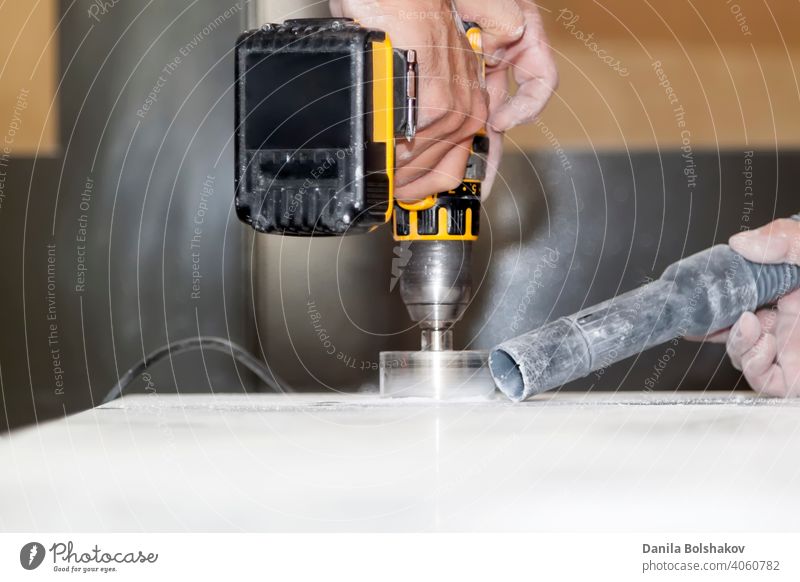 handyman cut round holes for electrical outlets in marble countertop for the kitchen using hand drill action appliance blade circle cleaner closeup construction