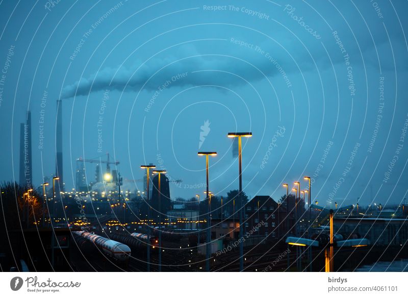Industrial landscape at the blue hour. Smoking industrial chimneys , freight trains on tracks and many lights Industry Chemical Industry co2 Smoke exhaust gases