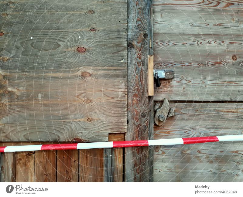 Rotweißes Absperrband vor einer Holzhütte mit Holztür aus rustikalem Holz mit Vorhängeschloss vor Beginn des Weihnachtsmarkt in der Hansestadt Lemgo bei Detmold in Ostwestfalen-Lippe
