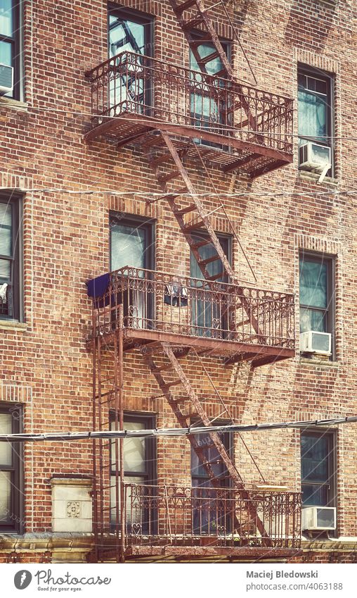 Old brick house building with iron fire escape, color toned picture, New York City, USA. city tenement NYC Manhattan townhouse retro old residential home effect