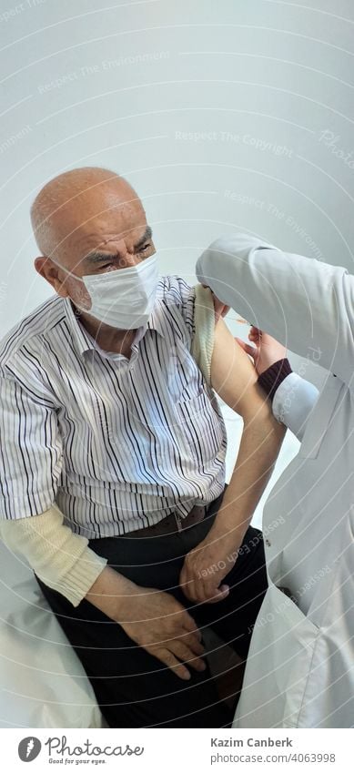 Old Turkish man getting Covid 19 vaccine to his arm by a nurse at a hospital covid 19 shot injection coronavirus pandemic epidemic old bearded turkish needle
