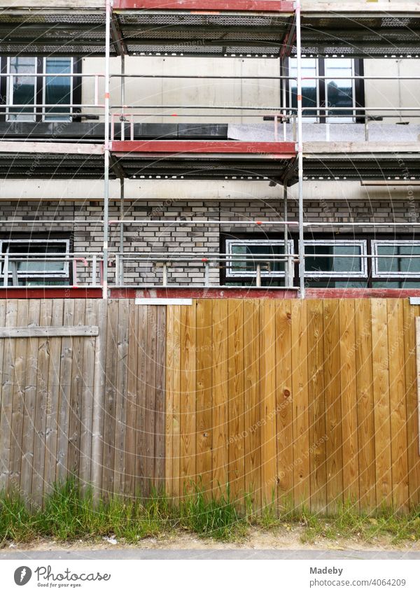 Weeds in front of a construction fence with wooden boards in front of a new building with scaffolding at the harbour in Offenbach am Main in HesseUrbanityUrban life