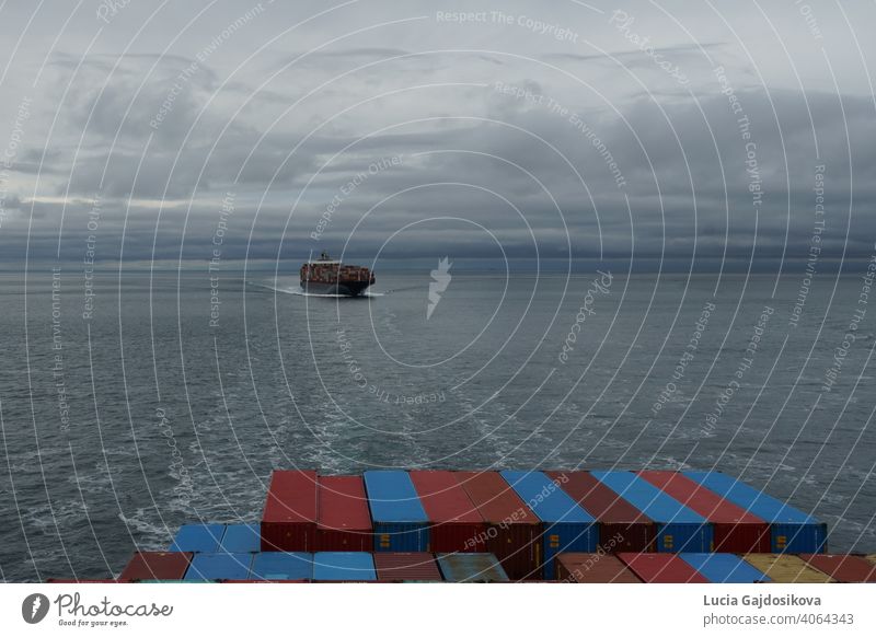 View on container vessel from other ship underway approaching the port of Vancouver, Canada, from Pacific ocean in the Salish Sea area. background bay blue boat