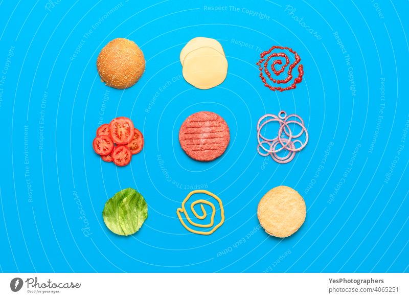 Burger ingredients top view isolated on blue background above view aligned arranged beef bread bun burger cheddar cheese cheeseburger colored concept cuisine