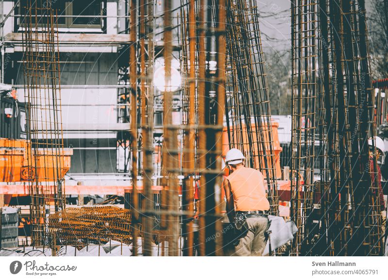 Construction worker next to steel girders Construction site Steel girder orange Tree Craftsperson Man Architecture Build Manmade structures Building Metal Crane