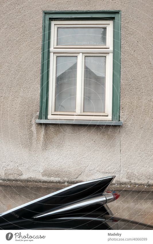 Big black rear fender of an american road cruiser of the fifties in front of the window of an old house at the Golden Oldies in Wettenberg Krofdorf-Gleiberg near Giessen in Hesse, Germany.