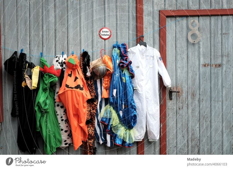 Colourful dresses and costumes on an old grey barn door at the flea market at the Golden Oldies in Wettenberg Krofdorf-Gleiberg near Gießen in Hesse Costume