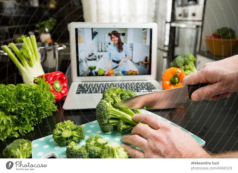 Beautiful happy woman streaming broadcast video blog about tasty and healthy food from home kitchen. Healthy lifestyle and social media. Man watching video recipe on laptop and cooking at home.