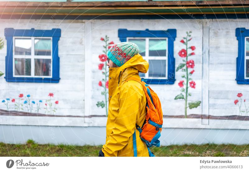 Travelling man in front of traditional wooden house, Poland cold winter backpack backpacker tourist young rural folk art tourist attraction polish