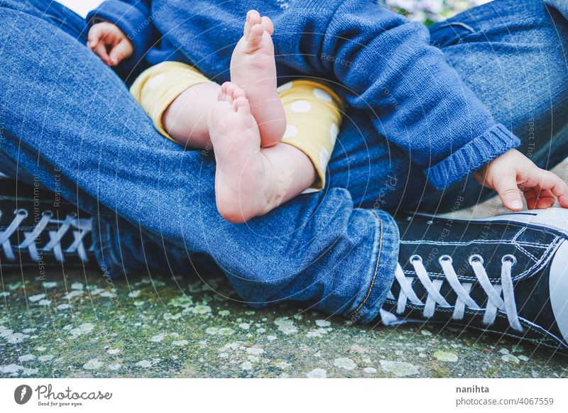 Close up of body parts of a baby of teenage fathers with her dad parent feet legs foot close close up casual sneakers barefeet teenage parenting family