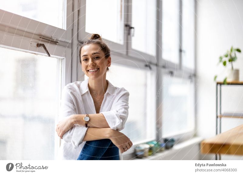 Portrait of a smiling creative woman in a modern loft space millennials student hipster indoors window natural girl adult one attractive successful people