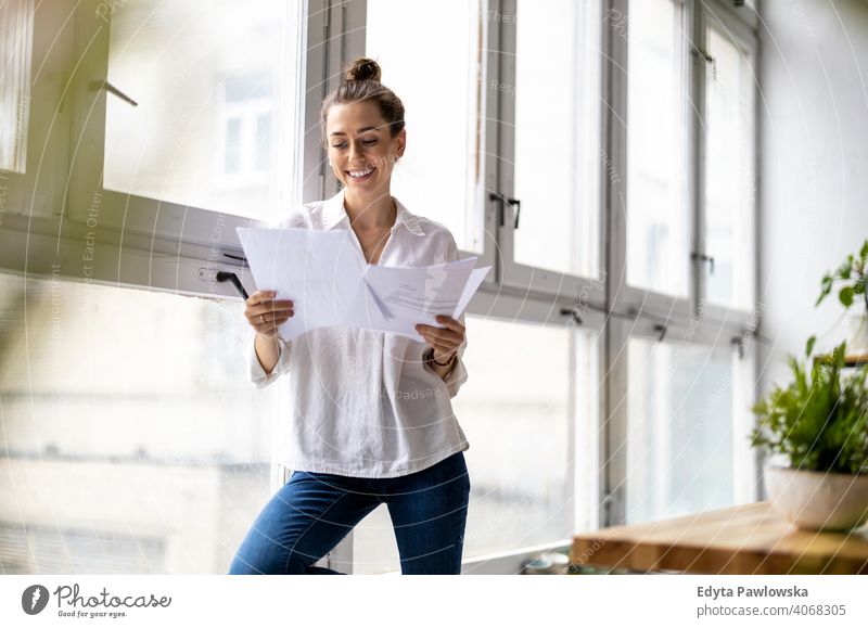 Young businesswoman looking at paperwork in an office millennials student hipster indoors loft window natural girl adult one attractive successful people