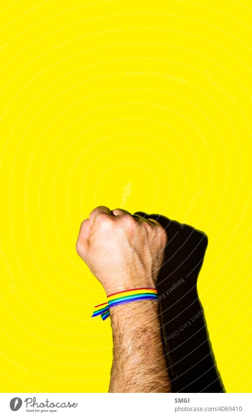A man's fist held high with a bracelet in the colors of the gay flag. celebrate celebration colorful colour community discrimination diversity equal equality