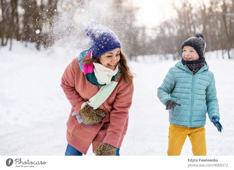 Mother and kid having snowball fight in winter park mother son daughter season together frozen cheerful fun people holiday forest childhood woman girl nature