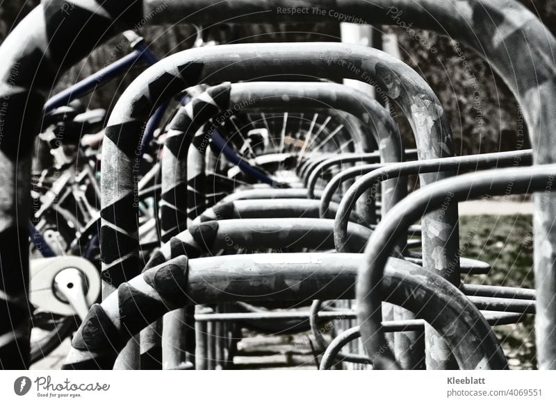 Black and white photograph Central view through a bicycle stand Wheel Bicycle rack Parking White black-white Metal Spokes Cycling Detail Street Exterior shot