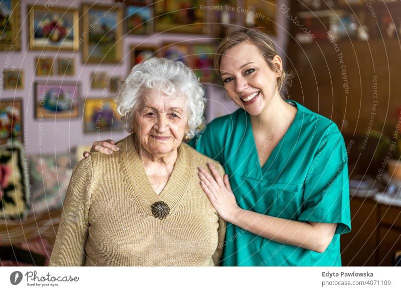 Friendly nurse supporting an elderly lady real people candid genuine woman senior mature female Caucasian home house old aging domestic life grandmother