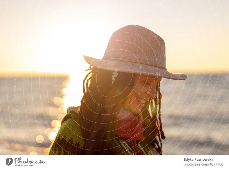 Young woman in a hat on the beach at sunset travel tourist tourism vacation backpacker beautiful attractive young adult people outdoors casual Greece happy joy