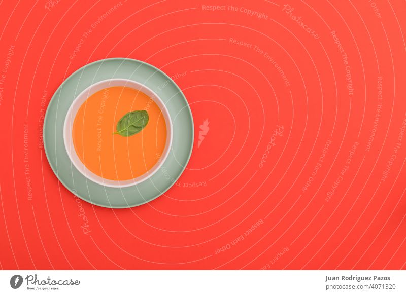 Minimalist image of a gazpacho bowl on a blue plate and red background. Top view. colorful creative delicious diet dish drink fresh geometry healthy legumes
