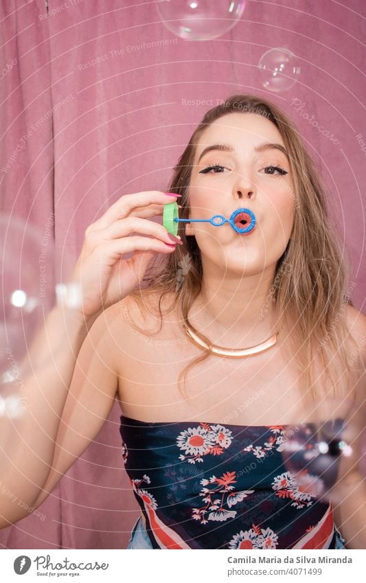 Happy woman making soap bubbles with pink background. adorable beautiful birthday celebration cheerful emotion emotions face fashion female funny girl glamour