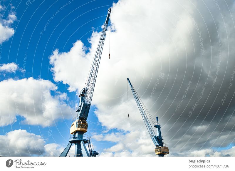 Two blue and yellow cranes in front of cloudy sky in a harbour Crane loading crane Blue sky Clouds Clouds in the sky Yellow Harbour Construction site