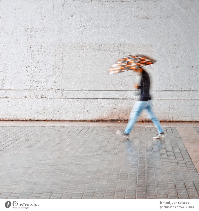 defocused man with an umbrella in rainy days in spring season people person raining water human pedestrian street city urban bilbao spain walking lifestyle