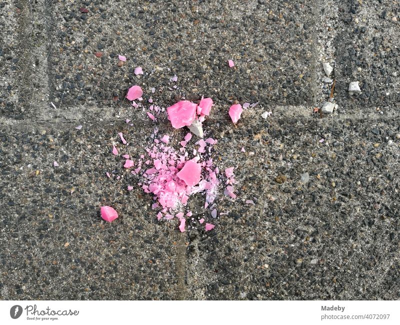 Dropped crumbled pink candy on grey pavement in Oerlinghausen near Bielefeld in the Teutoburg Forest in East Westphalia-Lippe Candy Lozenge Pink Broken Crumbs
