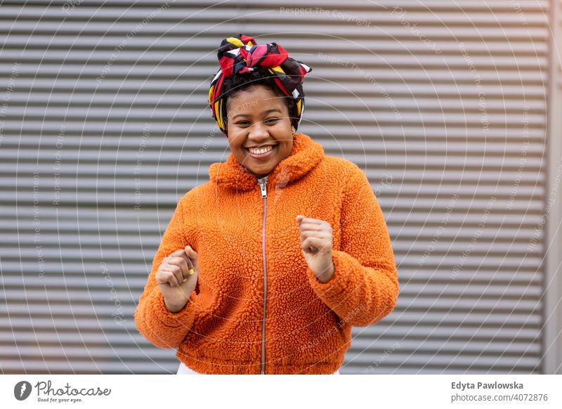 Happy young woman dancing in front of a wall one person alone outdoors day positivity confident carefree people adult casual beautiful attractive female smiling