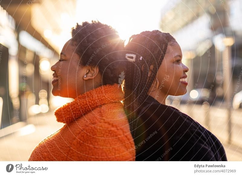 Two beautiful Afro american women standing back to back in city diversity diverse people love outdoors day positivity confident carefree woman young adult