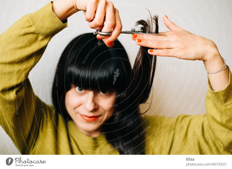 A brown haired woman cuts her own hair Haircut Hair Stylist do it oneself yourself at home Dark-haired recut lockdown DIY Hairdresser Woman Hair and hairstyles