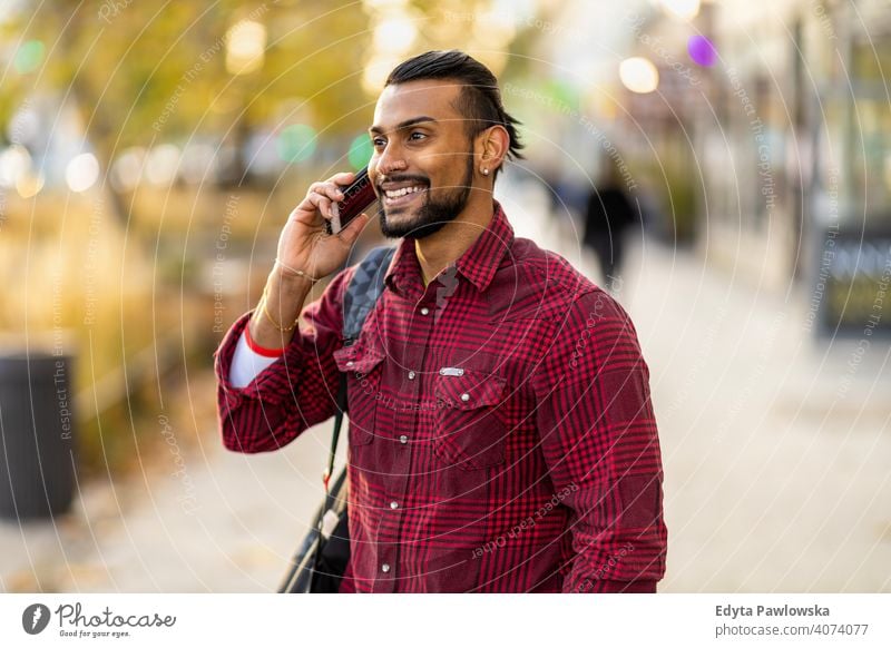 Handsome young man using mobile phone at the street Sinhalese asian Indian bearded outside urban standing outdoors city Warsaw casual lifestyle guy attractive