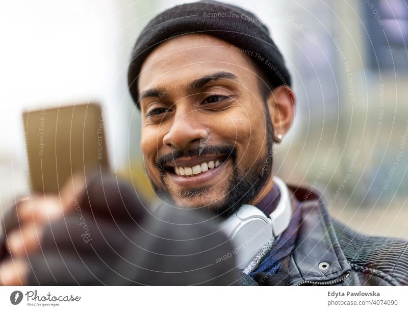 Handsome young man using mobile phone at the street Sinhalese asian Indian bearded outside urban standing outdoors city Warsaw casual lifestyle guy attractive