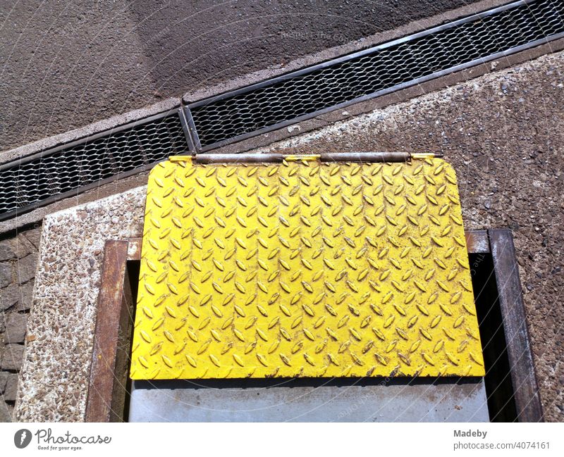 Yellow painted checker plate on a test bench in front of an old car workshop in sunshine in Wettenberg Krofdorf-Gleiberg near Giessen in Hesse, Germany