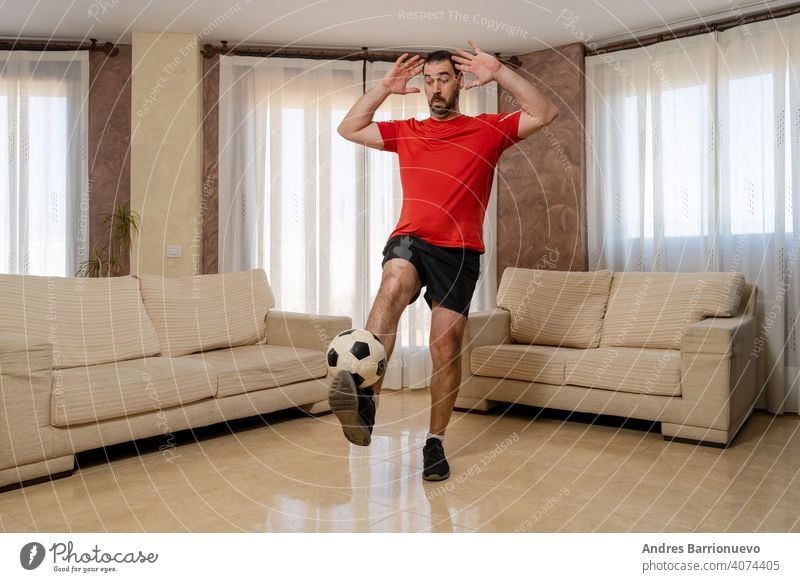 Bearded man in fit shape dressed in black and red sportswear controlling a soccer ball with his foot admirer adult home supporter person portrait fan emotion